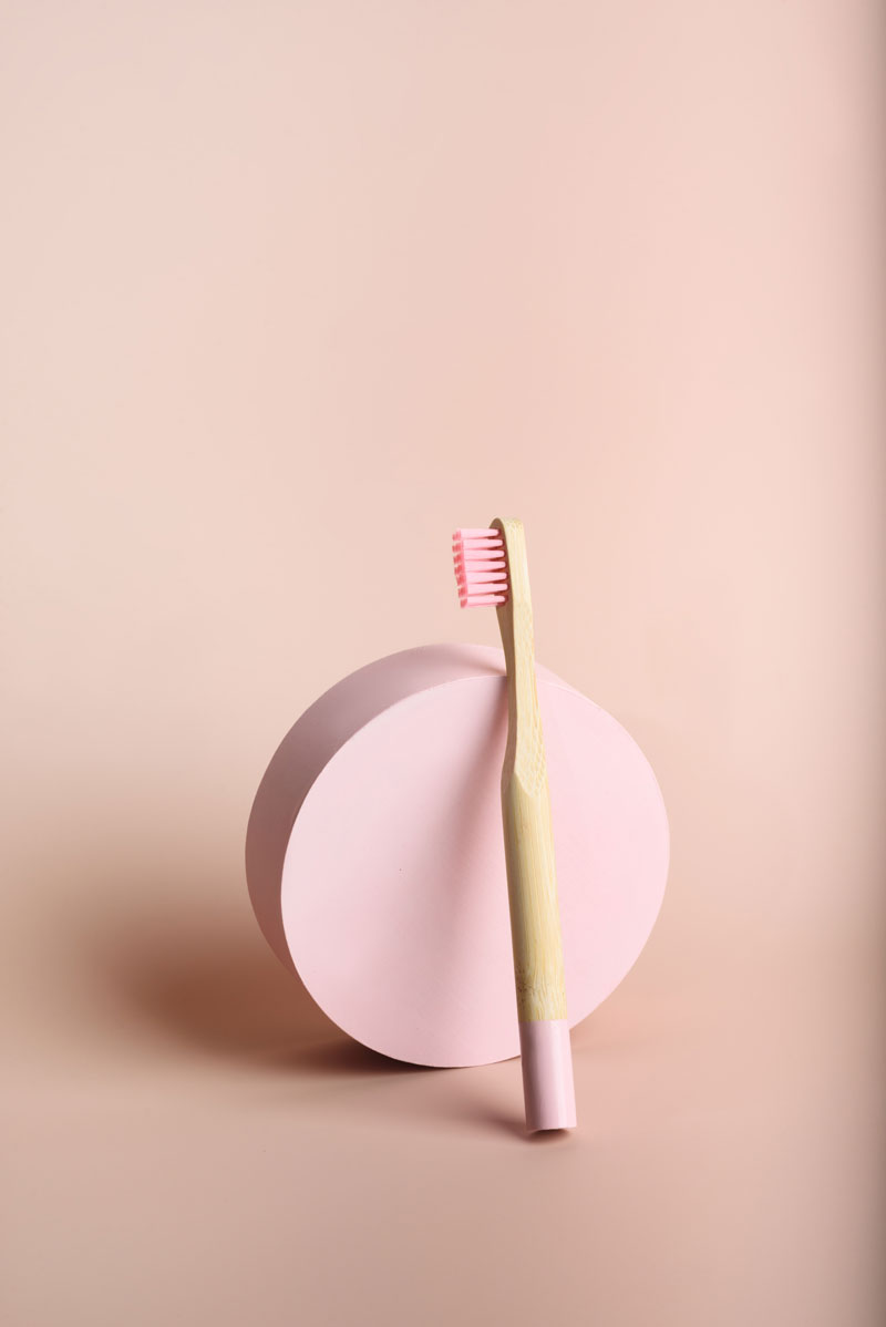 one-eco-friendly-natural-bamboo-toothbrush-near-circle-decor-on-pink-background